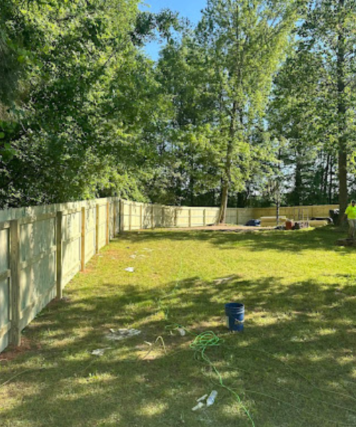 A yard with a fence and a trash can