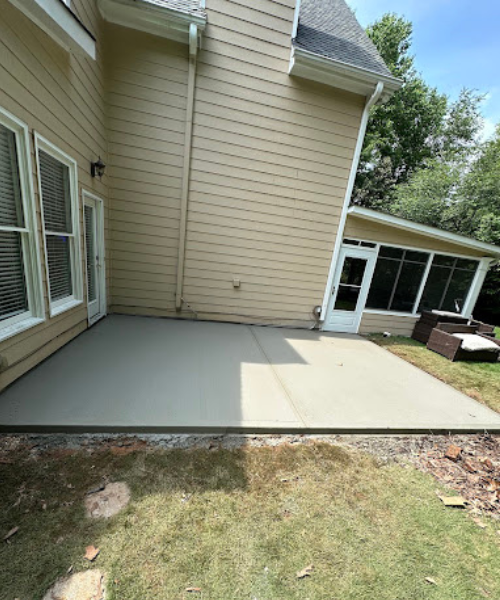 A back yard with a concrete patio in the middle of it