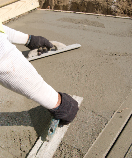 A person with gloves and gloves on laying concrete